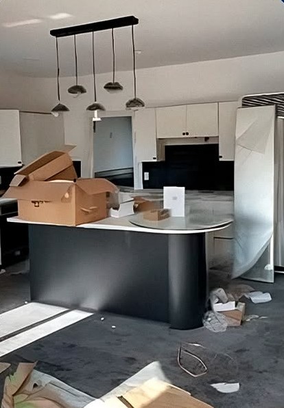 A new kitchen with packaging, boxes and building debris across the island and floor